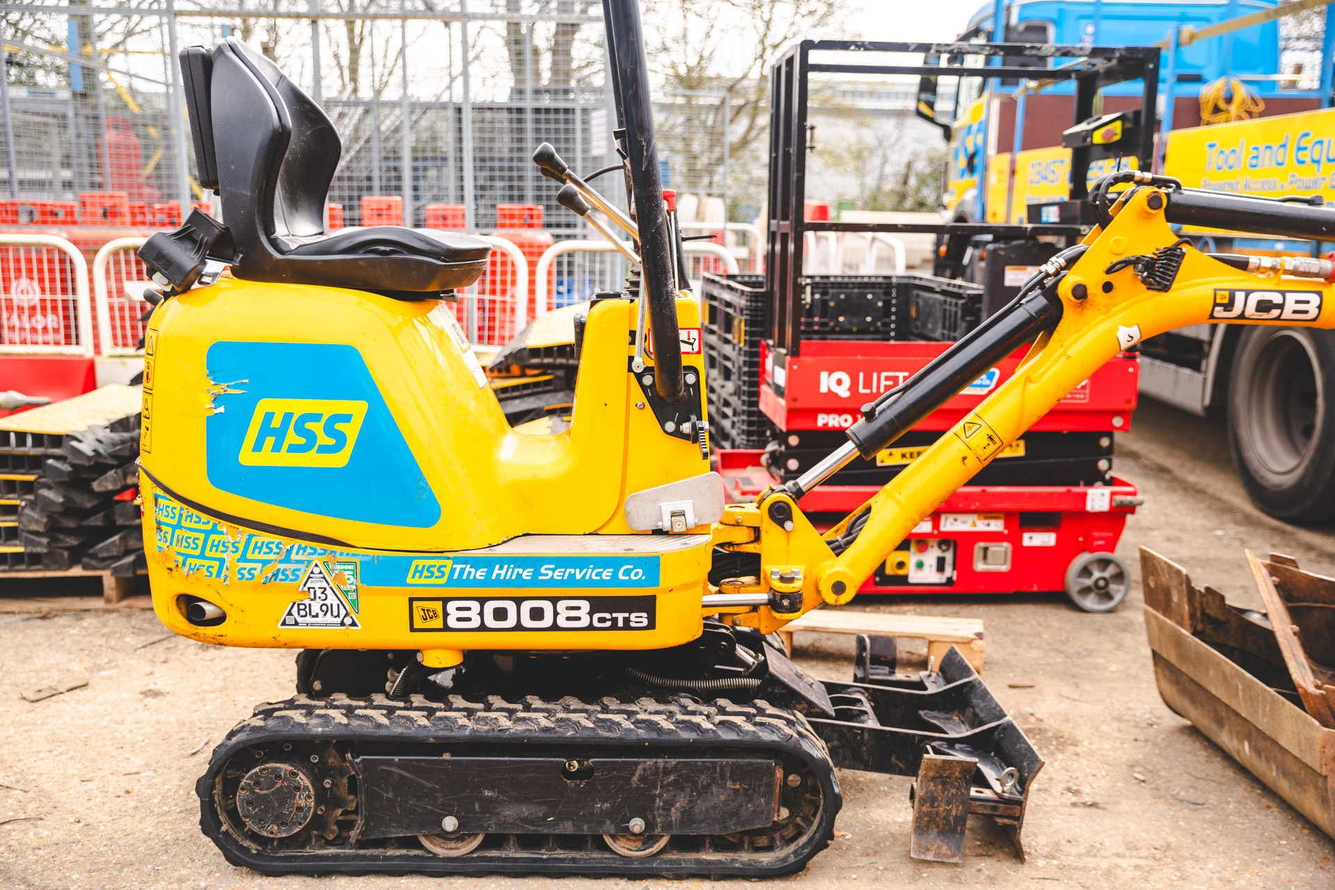 An mini excavator sits within a hire yard, representing the equipment and services that have shaped the HSS Hire brand over the years.
